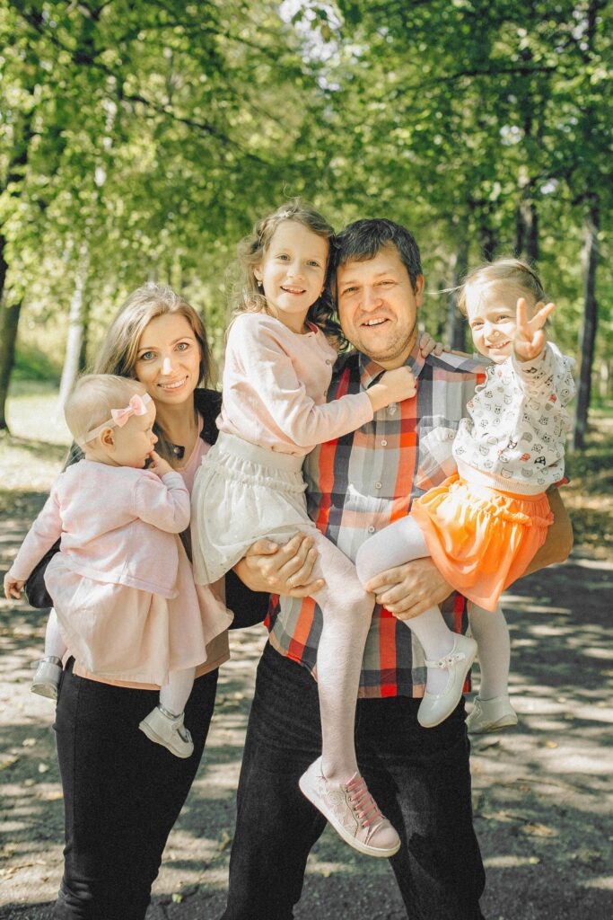 Growth Failure in Children (1–5 Years): Causes, Signs & Management A joyful family with parents and daughters bonding outdoors in a sunny park.